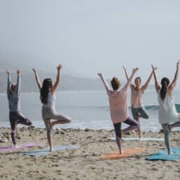 personen die groeps yoga doen op het strand